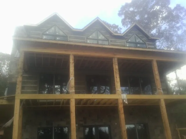 Dormers and porch framing on a large log home under construction — Roof Coating work by our crew in Northfield